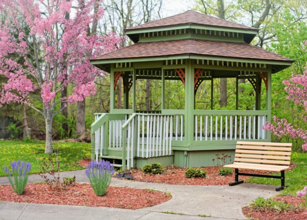 Taman dengan area duduk dan gazebo yang dikelilingi oleh tanaman hijau